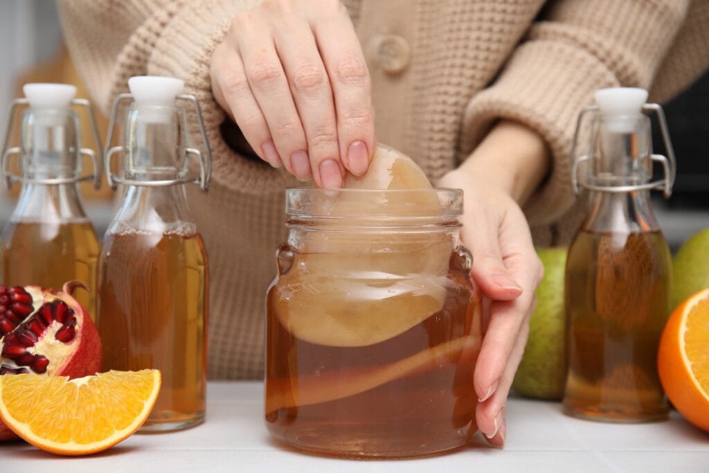 How to Make Kombucha at Home woman,making,homemade,fermented,kombucha,at,white,table,,closeup